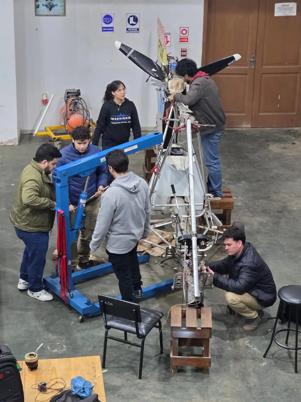 Vista desde arriba del taller: estudiantes colocan el motor y la hélice con un aparejo